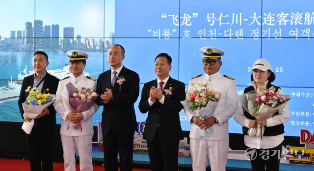 25일 인천 연수구 인천항 국제여객터미널에서 열린 '비룡'호 인천-다롄 정기선 여객운수항로 복항식에서 류쉐펑 다롄시 부시장과 박덕수 인천시 행정부시장이 첫 여객과 선장에게 꽃다발을 전달하고 기념촬영을 하고 있다. 조병석기자