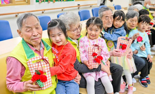 어버이날을 하루 앞둔 7일 오전 수원특례시 팔달구 팔달노인복지관에서 관내 어린이집 아이들이 어르신들에게 카네이션을 달아드린 뒤 포옹하고 있다. 윤원규기자