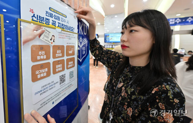 '건강보험 본인확인 의무화 제도' 가 시행된 20일 인천 서구 국제성모병원에서 병원 관계자가 신분증 지참을 알리는 안내문을 붙이고 있다.조병석기자