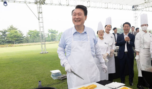 윤석열 대통령이 24일 서울 용산 대통령실 청사 잔디마당에서 열린 ‘대통령의 저녁 초대’ 출입기자단 초청 만찬 간담회에서 계란말이를 만들고 있다. 연합뉴스