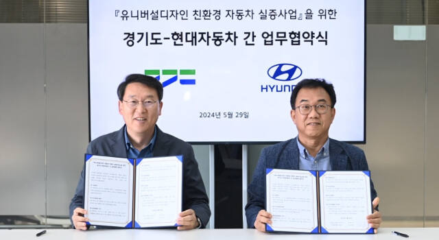 김상수 경기도 교통국장(왼쪽)이 유니버설디자인 친환경 자동차 실증사업을 위한 업무협약을 체결한 뒤 기념촬영하고 있다. 경기도 제공