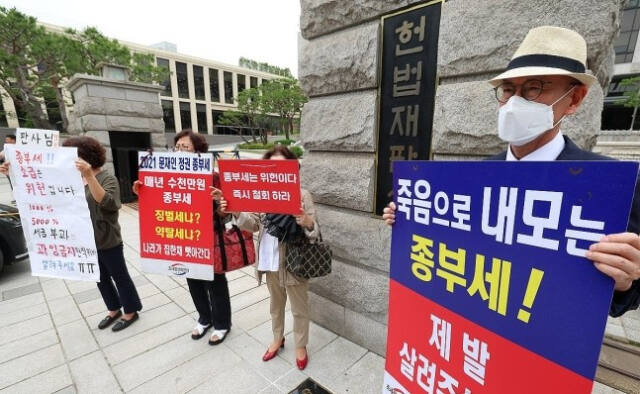 지난 30일 오후 서울 종로구 헌법재판소 앞에서 시민들이 종부세 규탄 피켓을 들고 서 있다. 연합뉴스