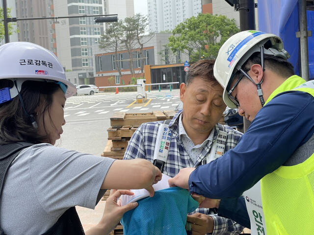 안전보건공단 직원들이 건설현장 직원의 안전모에 햇빛가리개를 부착하고 있다. 이대현기자
