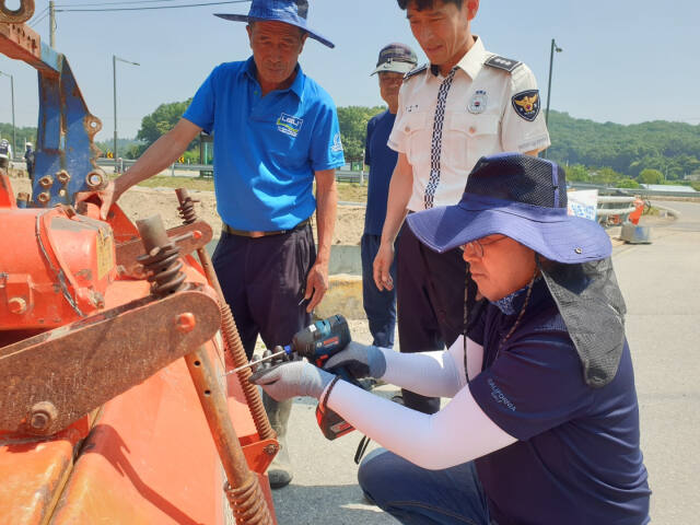 5일 조정권 한국교통안전공단 경기남부본부 본부장과 김지태 여주경찰서 교통과장이 농기계 교통사고 예방을 위해 후부반사판을 부착하고 있다. 공단 제공