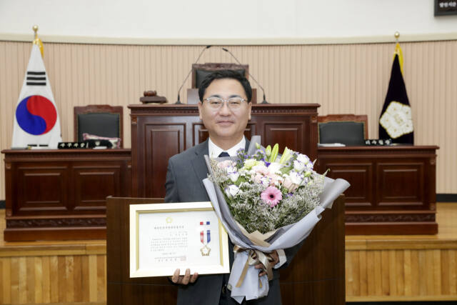 구리시의회 김성태 의원이 대한민국 시군 자치구 의장협의회에서 수여하는 대한민국지방의정봉사상을 수상한 뒤 수상패와 꽃다발을 들고 기념 촬영을 하고 있다.구리시의회 제공