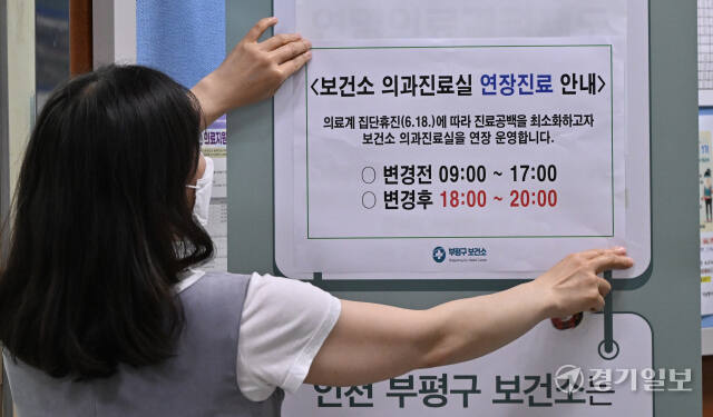 대한의사협회가 집단 휴진에 나선 18일 인천 부평구 부평보건소에서 직원이 의과진료실 연장진료를 알리는 안내문을 붙이고 있다.조병석기자