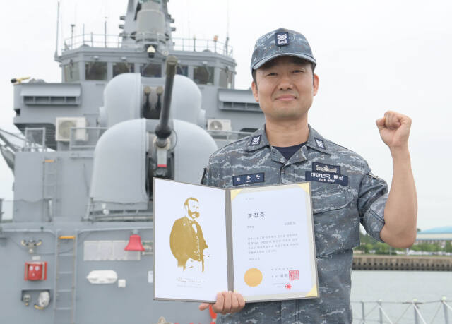 김종준 상사가 2함대 청주함 함수에서 헌혈 명예장을 들고 기념사진을 촬영하고 있다. 2함대 제공