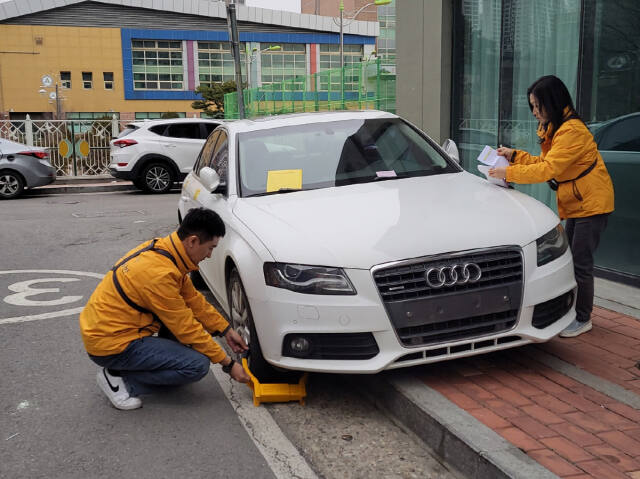 고양특례시 차량체납팀 직원들이 단속 차량 바퀴에 족쇄를 설치하고 있다. 고양특례시 제공