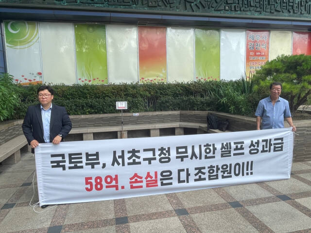 19일 서울 서초구 반포프라자에서 열린 신반포15차 조합 임시총회에서 성과급에 반대하는 조합원들이 ‘국토부, 서초구청 무시한 셀프 성과급 58억, 손실은 다 조합원이’라는 문구가 적힌 현수막을 들고 시위를 벌이고 있다. 하재인 기자