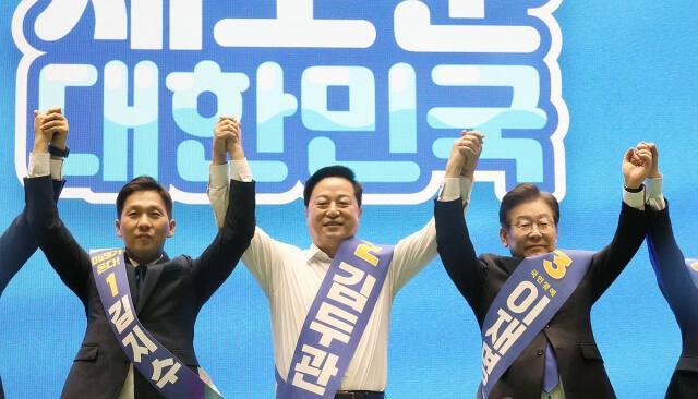 더불어민주당 새 지도부 선출을 위한 전당대회를 앞두고 20일 제주시 한라체육관에서 열린 합동연설회에서 김지수·김두관·이재명 대표 후보(왼쪽부터)가 손을 맞잡고 포토타임을 갖고 있다. 연합뉴스