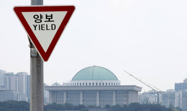 지난 4일 서울 마포구 서강대교에 설치된 교통표지판 너머로 국회의사당. ‘방송 4법’ 등 재의요구권을 놓고 여야가 양보 없는 벼랑끝 대치를 벌이고 있다. 연합뉴스