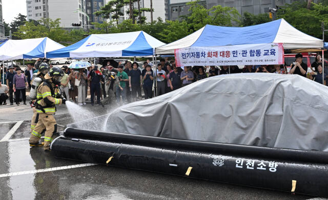 13일 인천 연수구 송도2동 행정복지센터 주차장에서 열린 전기자동차 화재대응 민·관 합동 시연 및 주민 대책 설명회에서 소방관들이 질식소화포와 전기차 수조탱크를 이용, 전기차 화재 진압 모의 시연을 하고 있다. 조병석기자