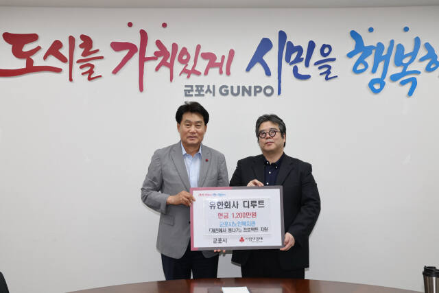 (유)디루트가 군포시에 저소득 청소년 지원 장학금을 기탁했다. 왼쪽부터 하은호 시장, 김대우 대표. 군포시 제공