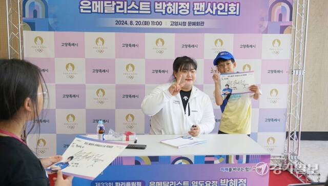 20일 고양시청 문예회관에서 열린 파리올림픽 역도 은메달리스트 박혜정 선수 팬 사인회에서 한 어린이가 사인을 받고 박 선수와 기념촬영을 하고 있다. 신진욱기자