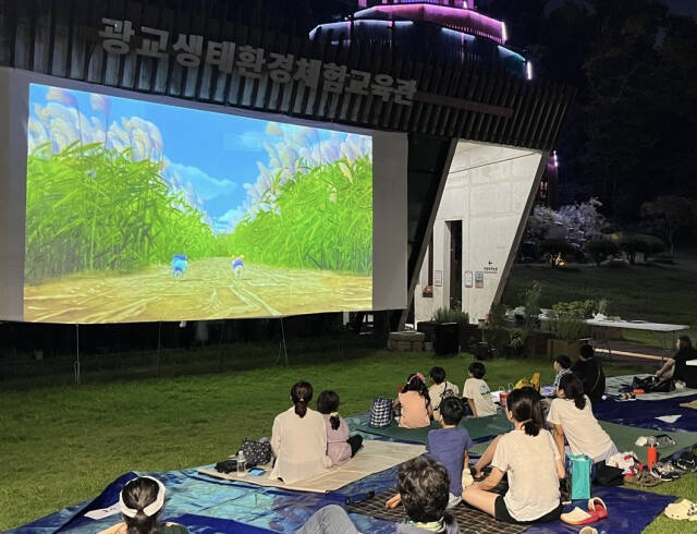 지난 8월30일 오후 광교호수공원에서 열린 제1회 초록극장 상영 행사를 찾은 시민들이 영화를 관람하고 있다. 광교생태체험교육관 제공