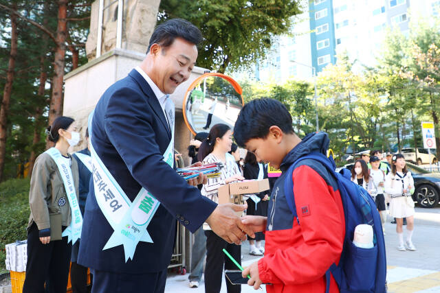 김성제 의왕시장이 24일 갈뫼초등학교에서 열린 어린이 교통안전 캠페인에 참여해 한 어린이와 악수를 하고 있다. 의왕시 제공