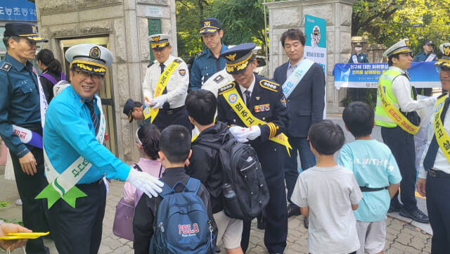 25일 최진태 남양주남부경찰서장과 관계자들이 등교하는 도농초등학교 학생들에게 학용품을 나눠주고 있다. 김태우기자