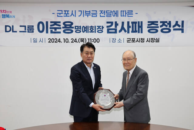 하은호 군포시장(왼쪽)이 24일 시장실에서 DL그룹(옛 대림산업) 이준용(86) 명예회장에게 감사패를 전달하고 있다. 군포시 제공
