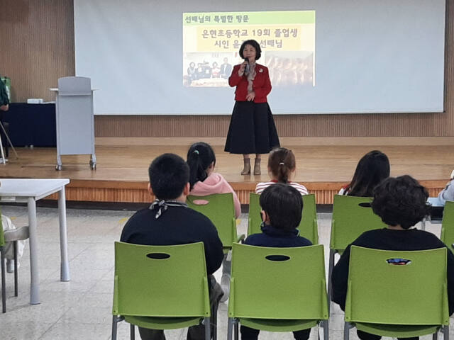 윤준경 작가가 모교인 은현초교를 방문해 자신의 동시집을 학생들에게 나눠주고 있다. 은현초교 제공