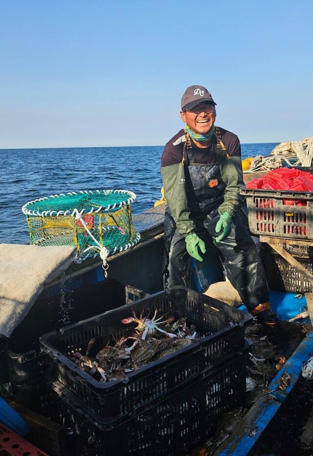 13일 오전 인천 옹진군 대청도 꽃게잡이 어선에서 한 어민이 꽃게를 바구니에 옮겨 담으며 활짝 웃고 있다. 독자 제공