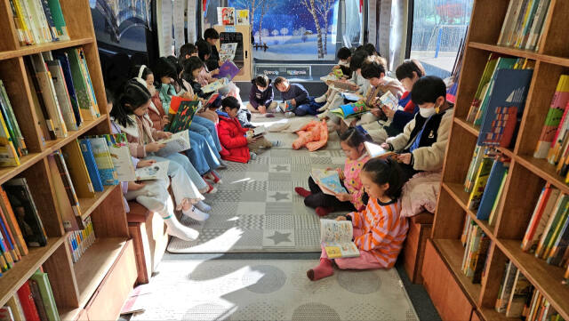 18일 오전 용인 수지구 새빛초등학교 운동장을 찾은 '책 읽는 버스'에서 1학년 학생들이 독서 체험 활동을 진행하고 있다. 새빛초교 제공
