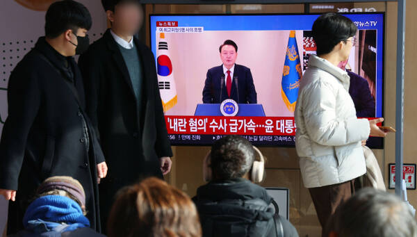 15일 서울역 대합실에서 시민들이 대통령 탄핵소추안 가결 관련 뉴스를 시청하고 있다. 연합뉴스