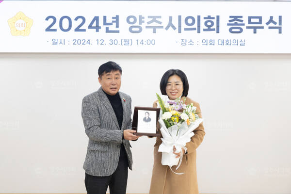 강혜숙 양주시의원(오른쪽)이 30일 시의회 대회의실에서 열린 시의회 종무식에서 윤창철 의장으로부터 경기도 북부시·군의회 의정활동 우수 의원 상패와 꽃다발을 전수받고 기념사진을 찍고 있다. 양주시의회 제공