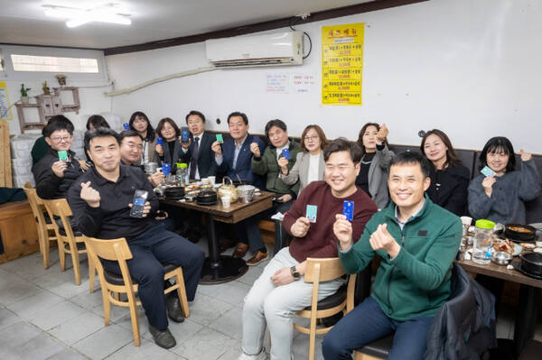 수원시 공직자들이 수원 지역경제 활성화를 위해 골목상권을 이용한 뒤 수원페이를 들어보이고 있다. 수원시 제공