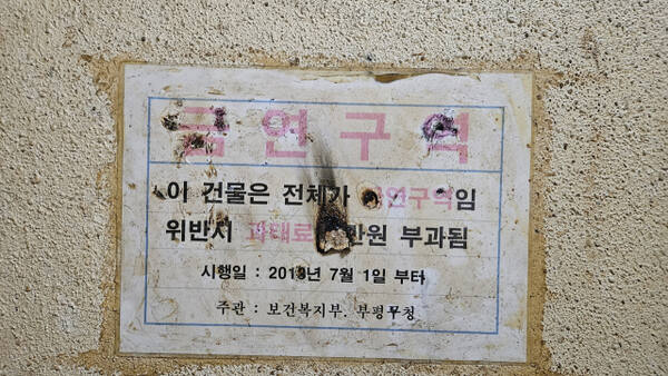 10일 인천 부평구 테마의 거리의 한 건물 비상계단에 부착한 금연구역 경고장이 훼손된 채 관리하지 않고 있다. 장민재 기자
