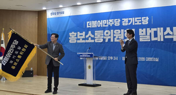 김승원 더불어민주당 경기도당위원장(왼쪽)과 황대호 도당 홍보소통위원장이 9일 오후 경기도의회 대회의실에서 열린 더불어민주당 경기도당 홍보소통위원회 발대식에서 회기를 흔들며 출범을 알리고 있다. 김경희기자