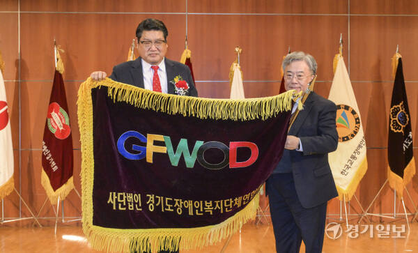 17일 오후 경기아트센터 컨벤션홀에서 열린 '(사)경기도장애인복지단체연합회장 이취임식'에서 제7대 이세항 회장이 제8대 이영재 회장에게 협회기를 전달하고 있다. 윤원규기자