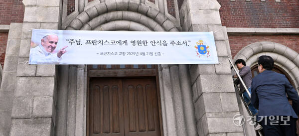 22일 인천 중구 중구 답동 성당에서 건물 외벽에 프란치스코 교황 선종을 애도하는 플래카드를 설치하고 있다.조병석기자