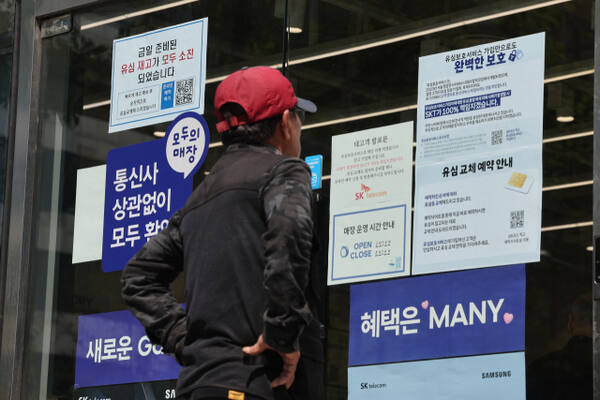 유심 재고 소진 및 유심보호서비스 관련 안내문을 살펴보고 있는 시민. 연합뉴스