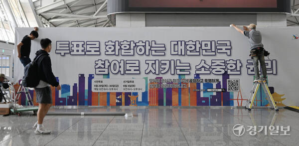 21대 대통령선거 사전투표를 앞둔 27일 인천공항 1터미널 출국장에 인천선관위 관계자들이 사전투표소에 대형 안내 홍보물을 붙이고 있다. 조병석기자