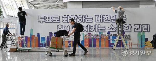 21대 대통령선거 사전투표를 앞둔 27일 인천공항 1터미널 출국장에 인천선관위 관계자들이 사전투표소에 대형 안내 홍보물을 붙이고 있다. 조병석기자