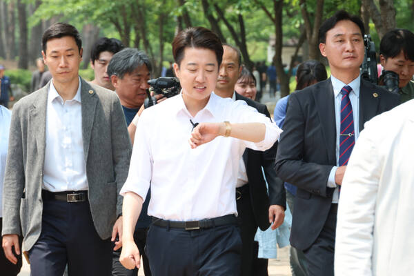 개혁신당 이준석 대선 후보가 사전투표를 하루 앞둔 28일 서울 여의도공원에서 점심시간을 이용해 산책 나온 직장인들에게 지지를 호소하던 중 시계를 보고 있다. 연합뉴스