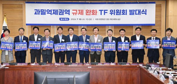 지난해 7월 국회에서 열린 ‘과밀억제권역 규제완화 TF 위원회 발대식’에서 참석자들이 과밀억제권역 완화를 위한 손팻말을 들고 있다. 수원시 제공