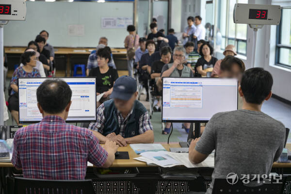 이재명 정부의 첫 대규모 경기 부양책인 '민생회복 소비쿠폰' 신청이 시작된 21일 오전 수원특례시 인계동 행정복지센터에서 시민들이 소비쿠폰을 신청하고 있다. 신청 첫 주인 21∼25일에는 시스템 과부하와 주민센터 혼잡 방지를 위해 출생 연도 끝자리 기준 요일제를 운영한다. 끝자리 1·6은 월요일, 2·7은 화요일, 3·8은 수요일, 4·9는 목요일, 5·0은 금요일에 신청할 수 있다. 주말에는 온라인 신청만 할 수 있다.