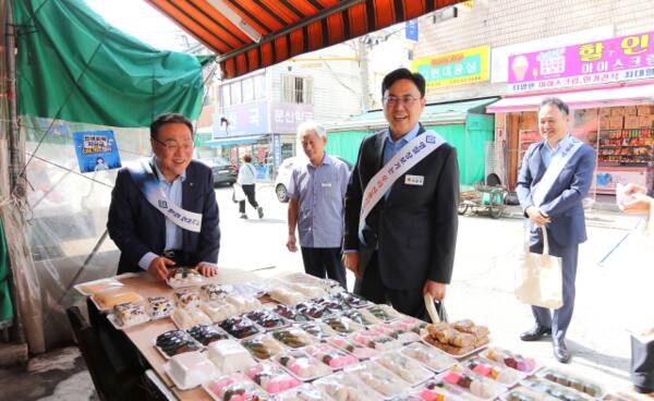 시석중 경기신용보증재단 이사장(왼쪽)과 이용욱 경기도의원(오른쪽)이 2일 파주 전통시장을 찾아 제수용품을 구입하고 있다. 경기신보 제공.