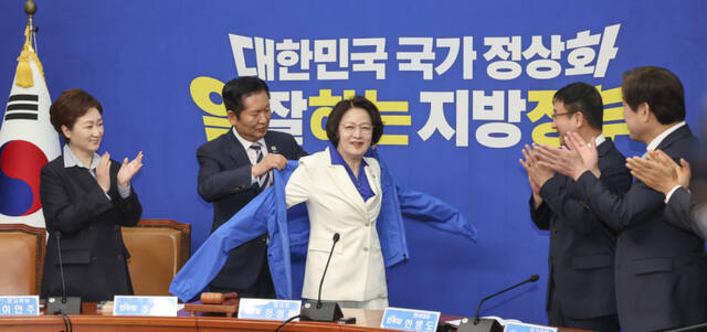 더불어민주당 정청래 대표가 13일 국회에서 최고위원회의에 앞서 열린 추미애 경기도 지사 후보 환영식에서 추 후보에게 선거용 점퍼를 입혀주고 있다. 연합뉴스