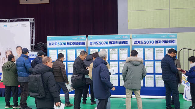 지난해 12월 광명시민체육관에서 열린 ‘경기도 5070 일자리박람회’에서 참가자들이 구직 안내문을 살펴보고 있다. 한준호기자